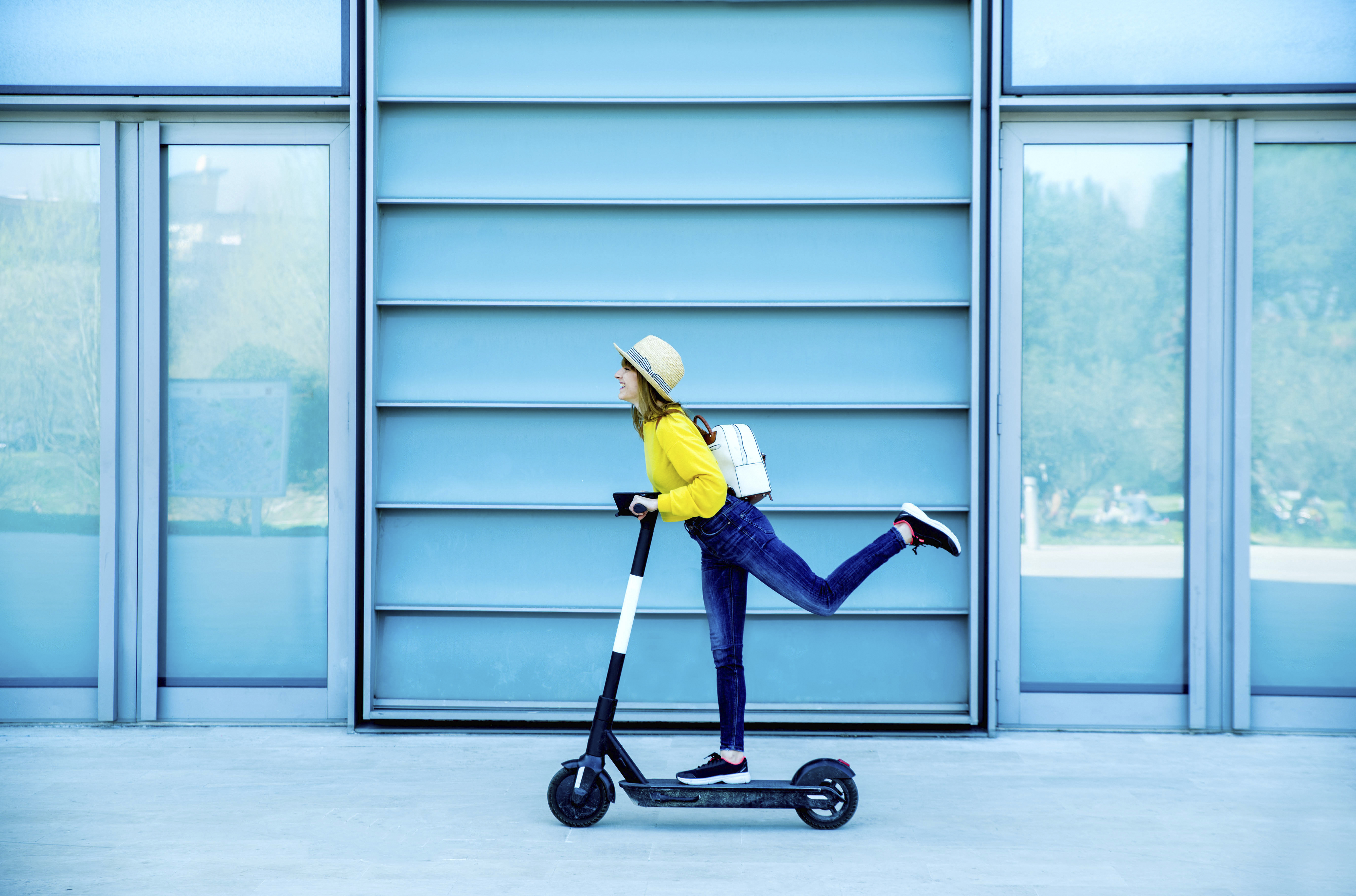 Young woman enjoying electric scooter ride on footpath