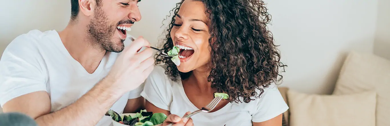 Pareja dándose de comer verduras con un tenedor